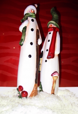 Zwei Schneemänner im Schnee vor rot