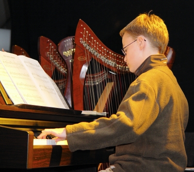 Kind am Klavier mit Harfe im Hintergrund