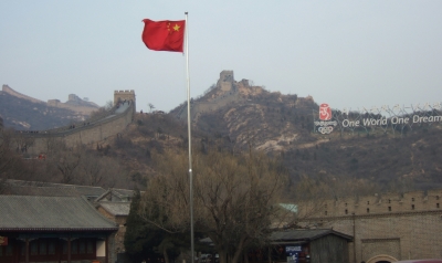 Große Mauer mit Olympia-Werbung und roter Flagge