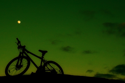 Silhouette eines Fahrrades bei Nacht (grüner Hintergrund)