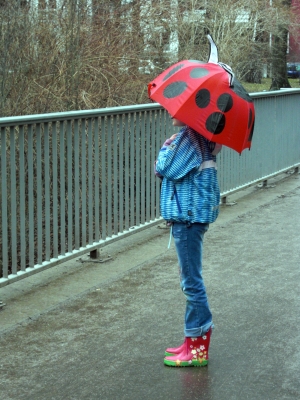 Kind mit Regenschirm auf Brücke