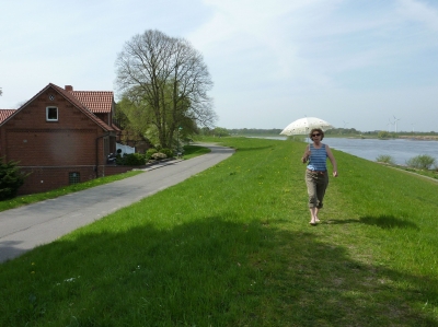 Frau mit Sonnenschirm auf einem Deich an der Elbe