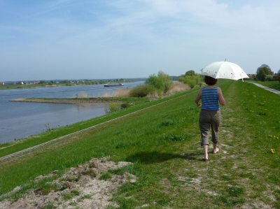 Frau mit Sonnenschirm auf einem Deich an der Elbe