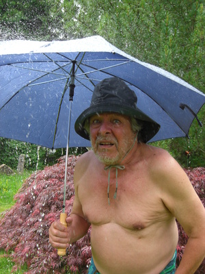 Senior im Regen mit Regenschirm
