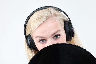Frau mit Kopfhörer hinter Schallplatte