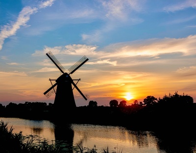 Windm&uuml;hle am Fluss mit sonnenuntergang