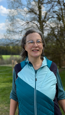 L&auml;chelnde Frau mit Brille in Sportjacke im Fr&uuml;hling