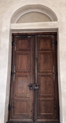 Historisches Holzportal mit Kassettenfeldern und Eisenbeschl&auml;gen in Rundbogennische